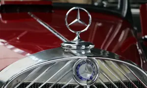Detaljerad bild av Mercedes-Benz-emblemet på en röd klassisk bil. Detta är ett av de första bilmärkena som skapades.