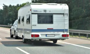 Samochód ciągnie przyczepę kempingową Hobby Excellent. Kierowca z kodem 96 prawo jazdy cieszy się podróżą.