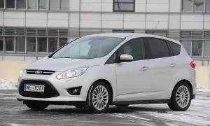 Srebrny Ford C-Max z włączonymi przednimi światłami, gotowy do jazdy w zimowych warunkach.