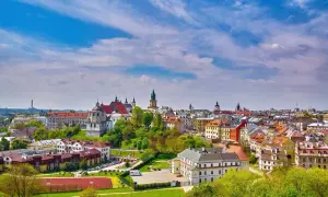 Widok na malownicze miasta w lubelskim z dominującymi kościołami i kolorowymi kamienicami pod błękitnym, chmurowym niebem.