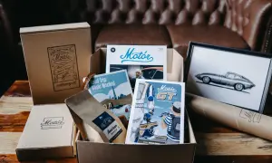 Zestaw prezentowy z magazynami motoryzacyjnymi, kawą i obrazem klasycznego samochodu.