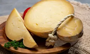Kawałki żółtego sera, w tym okrągły z widocznym sznurkiem, i trójkątny kawałek, prezentują bogaty aromat affumicata.