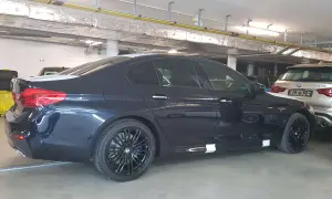 Ciemnogranatowe BMW 520d xDrive z czarnymi felgami stoi w garażu.
