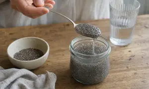 Mano versa semi di chia in un barattolo, creando una sostanza gelatinosa. Attenzione, i semi di chia possono essere pericolosi se non idratati.