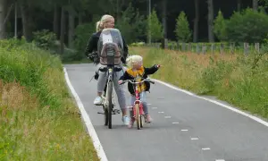 Mama i córka na rowerach odkrywają rodzinne trasy rowerowe. Dziecko wskazuje drogę.