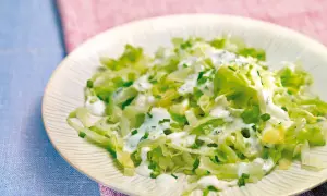 Frischer Spitzkohlsalat mit cremigem Dressing und Schnittlauch auf einem Teller.