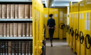 Rayons de livres anciens dans les archives départementales d'Indre-et-Loire en ligne, une personne se déplace dans l'allée.