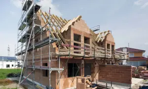 Rohbau firma im Einsatz: Ein Haus im Bau mit Gerüst, Ziegelwänden und Dachstuhl.