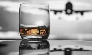 Szklanka whisky z lodem na tle samolotu. Czy można przewozić alkohol w samolocie Ryanair?