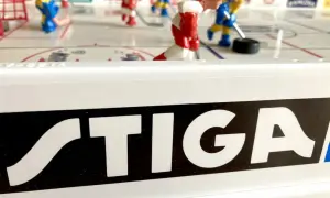 Stig Hjelmquist spelar hockey på STIGA-bordet. Röda och blå spelare kämpar om pucken på isen.