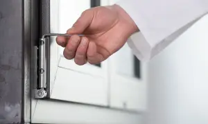 Dłoń z kluczem imbusowym reguluje zawias okna. Przygotowanie do trybu zimowego regulacja okien na zimę.