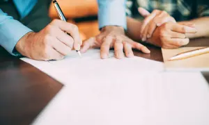 Mężczyzna podpisuje dokumenty, które mogą być podstawą do wydania aktu urodzenia.
