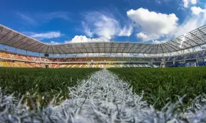 Piękny, pusty stadion Podbeskidzie z kolorowymi trybunami i zieloną murawą pod błękitnym niebem.