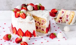 Eine köstliche Erdbeer Raffaello Torte, umhüllt von Kokosraspeln und dekoriert mit frischen Erdbeeren und Raffaello Kugeln.