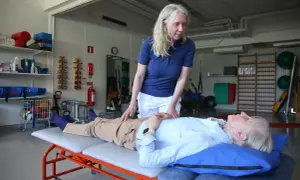 Fysioterapeut undersöker en patient som ligger på en brits. Patienten verkar vara fixerad bebis i sin position, redo för behandling.
