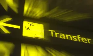 Żółty znak lotniskowy z ikoną samolotu i napisem "Transfer". Czy można opuścić lotnisko podczas przesiadki?