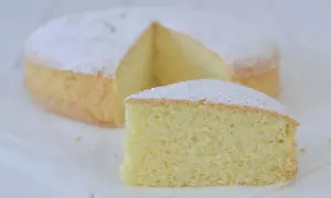 Una soffice torta con farina di riso, spolverata di zucchero a velo, con una fetta tagliata.