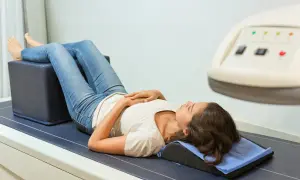 Jeune femme allongée pour un examen, peut-être pour évaluer une ostéopénie et ses douleurs associées.