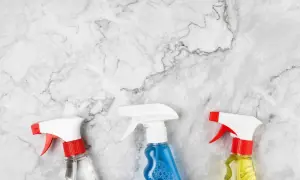 Tre flaconi spray su marmo bianco, pronti per scoprire come pulire il marmo macchiato.