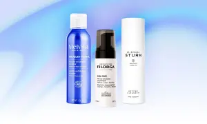 Tre flaconi di prodotti per la cura della pelle, tra cui una polvere esfoliante e due detergenti enzimatici, su sfondo blu sfumato.