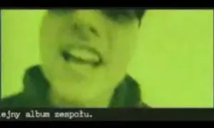 Fragment klipu zespołu Kaliber 44. Widać twarz rapera na zielonym tle. Tekst: "ejny album zespołu.