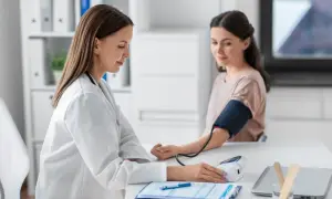 Lekarz medycyny pracy mierzy ciśnienie pacjentce. Po ilu dniach zwolnienia lekarskiego można wrócić do pracy?