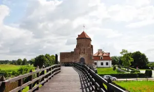 Drewniany most prowadzi do ceglanego zamku z czerwoną wieżą. Idealne ciekawe miejsca 100km od Warszawy na weekendową wycieczkę.