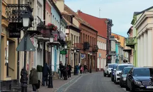 Urokliwa ulica w Koninie z kolorowymi kamieniczkami, balkonami i ludźmi spacerującymi po bruku. Odkryj **konin atrakcje** spacerując tymi uliczkami.