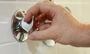 Hand dreht am Duschthermostat, um den wasseranschluss abzudichten.