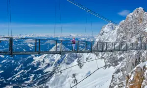Most na Dachstein Glacier, gdzie turystka podziwia zimowy krajobraz Alp.