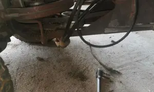 Jak założyć pasek do kosiarki traktorka Husqvarna? Widok mechanizmu napędowego z kluczem nasadowym.