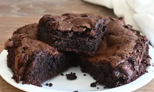 Una torta cioccolatino ricca e umida, tagliata a fette su un piatto bianco. La superficie è leggermente screpolata, con cristalli di sale visibili.