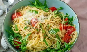 Spaghetti mit Rucola, Kirschtomaten und Parmesan in einer Schüssel.