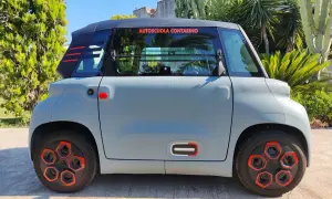 Citroën Ami grigia parcheggiata all'aperto, con dettagli rossi e neri. La scritta "Autoscuola Contarino" sul finestrino suggerisce un uso per l'apprendimento, con un'ottima **citroen ami autonomia** per la città.