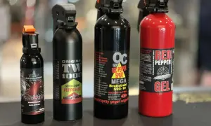 Cztery różne pojemniki z gazem pieprzowym, w tym jeden czerwony z napisem "RED PEPPER GEL".
