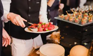 Kelner serwuje truskawki, prezentując różne metody serwowania potraw. Obok widać eleganckie przekąski.