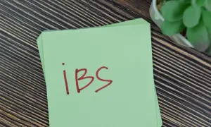 Zielona kartka z napisem "ibs" na drewnianym tle. Może to być przypomnienie o potrzebie leczenia, np. lekiem Duspatalin.