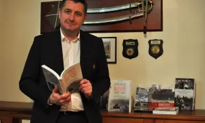 Un homme lit un livre sur l'histoire de la 1re division blindée polonaise. Le nom "Switek" pourrait être lié à l'origine de ce nom, peut-être un ancêtre ou un lieu.