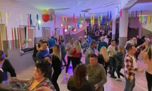 Wesoła zabawa w remizie, ludzie tańczą przy muzyce. Kolorowe serpentyny i balony tworzą świąteczną atmosferę.