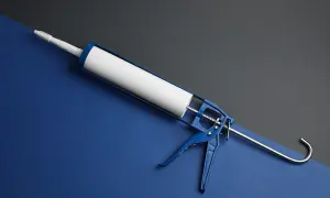 Niebieski pistolet do silikonu z białą tubą na tle dwóch kolorów.