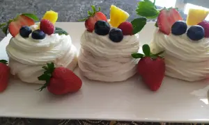 Mini bezy pavlova z bitą śmietaną, truskawkami, borówkami i ananasem.
