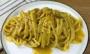 Un piatto di pasta alla milanese cremosa, con fili di zafferano e pepe nero.