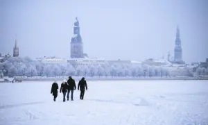 Familie spaziert über zugefrorene Daugava in Riga, Lettland im Winter. Die Stadt mit ihren Türmen ist im Schnee versunken.