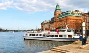 En vit passagerarbåt ligger vid kajen i Stockholm. En båttur här ger fin utsikt över stadens vackra byggnader och vattnet.
