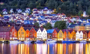 Bunte Holzhäuser am Wasser, ein Traum für Bergen Sightseeing. Boote spiegeln sich im Abendlicht.