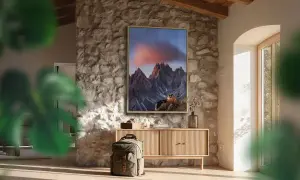 Quadro con montagne al tramonto, che cattura vibranti spazi colore. Zaino e mobile in legno completano l'arredo rustico.
