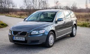 Szary Volvo V50 2.0D na drodze, z drzewami w tle.