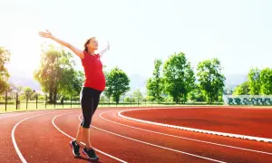 Donna incinta con le braccia aperte su una pista da corsa, dimostra che si può correre in gravidanza.