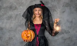 Kobieta w stroju czarownicy z dynią i latarenką. Inspiracja, jak się ubrać na Halloween.