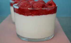 Délicieuse panna cotta à la vanille, surmontée d'un coulis de framboise et de framboises fraîches. Un dessert léger et fruité.